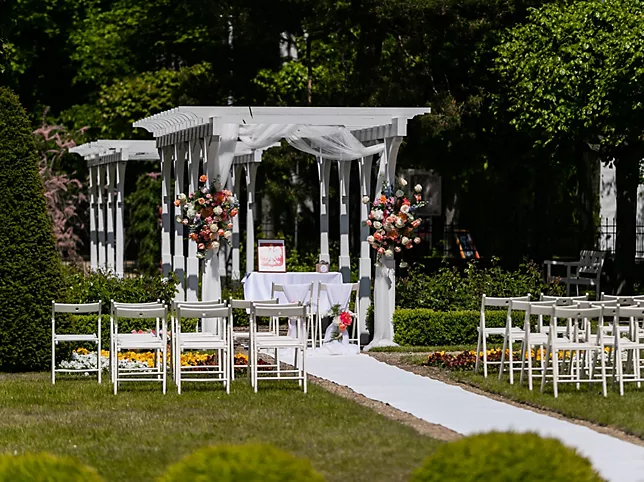 A pyramid stack of empty crystal champagne coupe glasses on a glass table with a dark background and soft lighting.