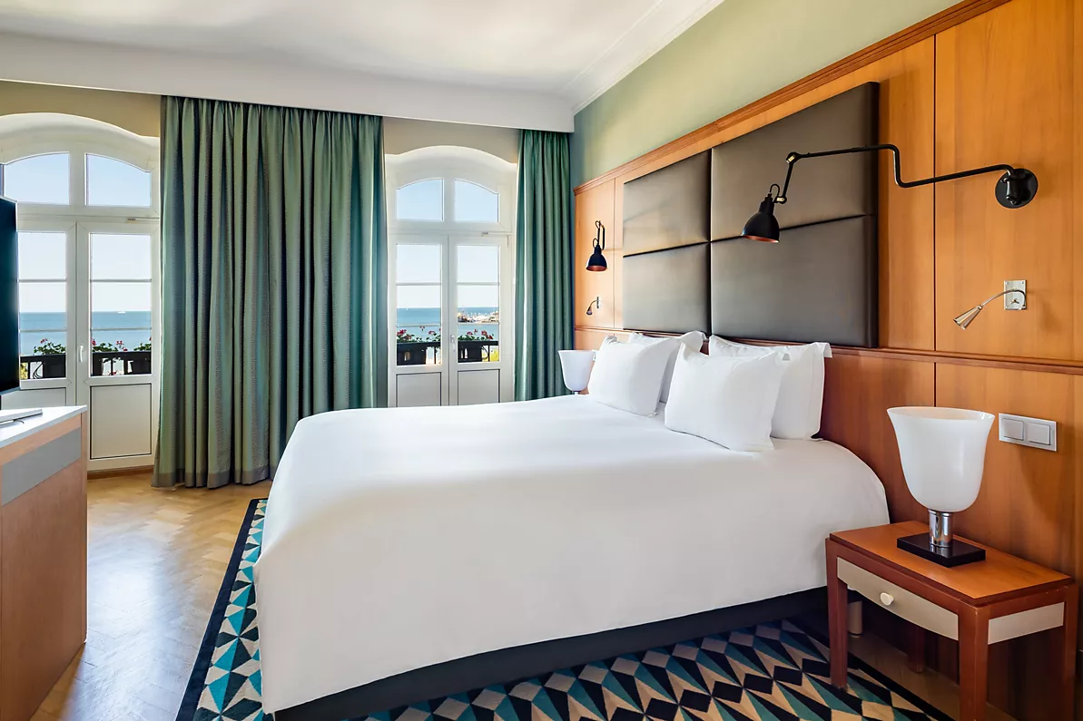 A pyramid stack of empty crystal champagne coupe glasses on a glass table with a dark background and soft lighting.