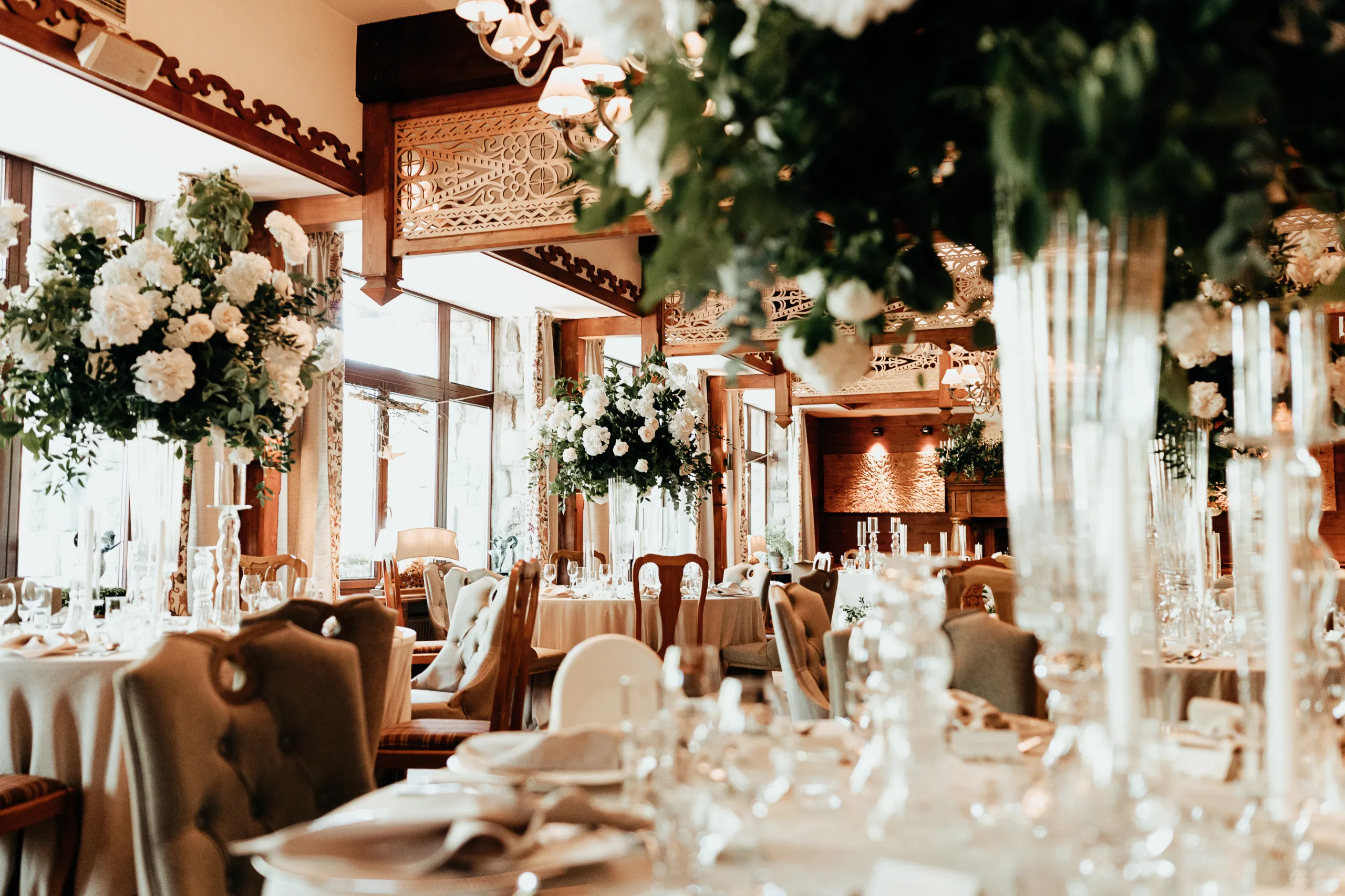 A pyramid stack of empty crystal champagne coupe glasses on a glass table with a dark background and soft lighting.