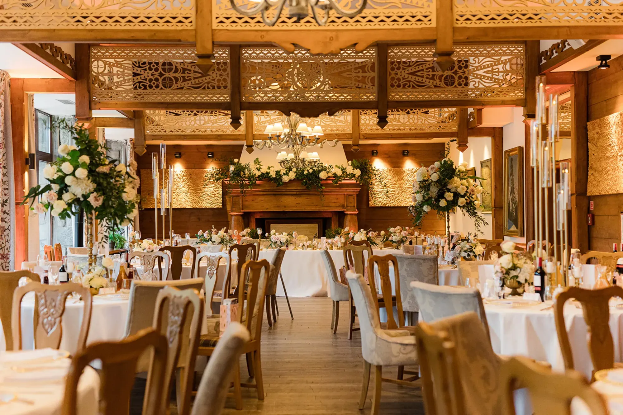 A pyramid stack of empty crystal champagne coupe glasses on a glass table with a dark background and soft lighting.