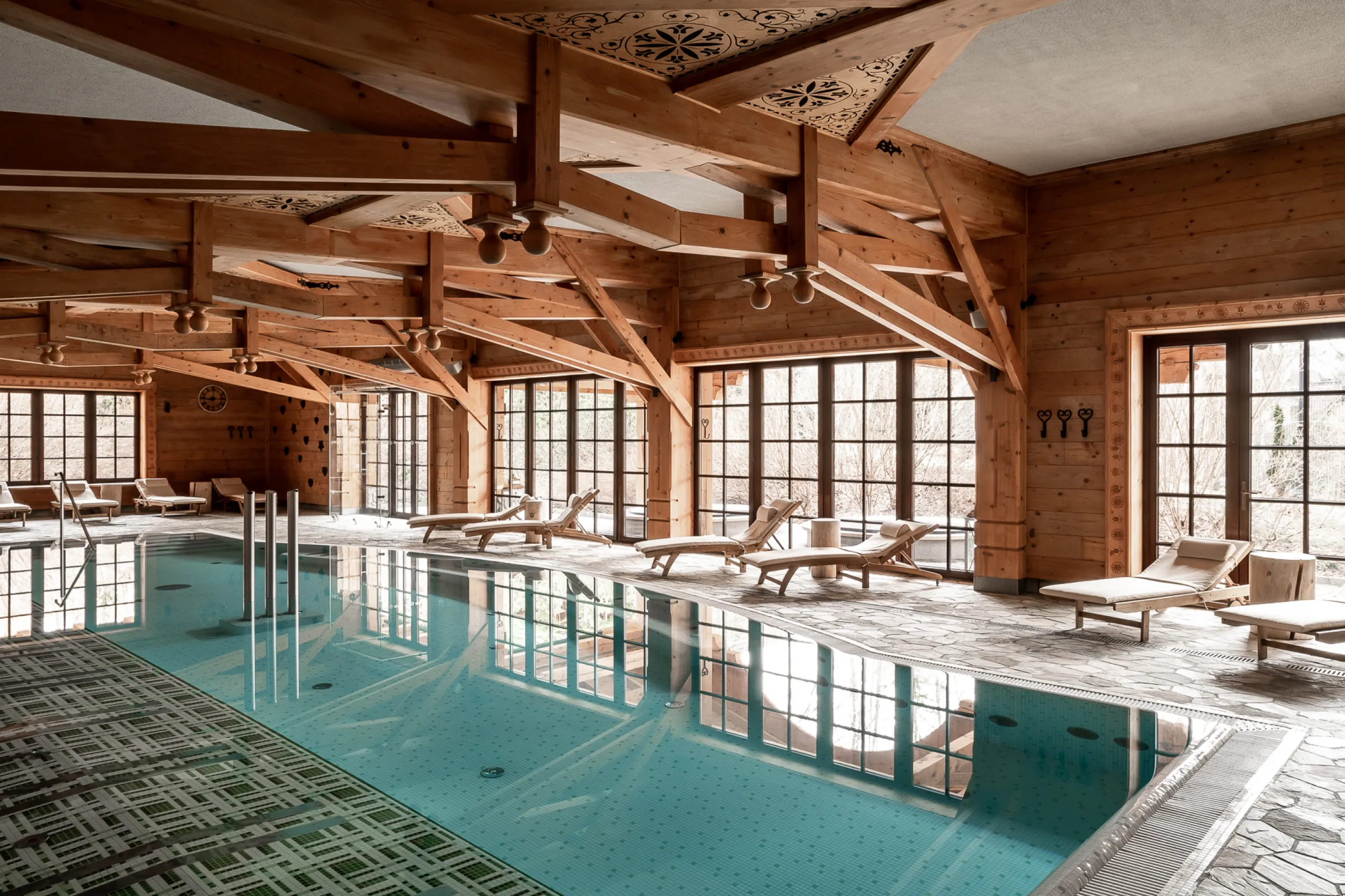 A pyramid stack of empty crystal champagne coupe glasses on a glass table with a dark background and soft lighting.