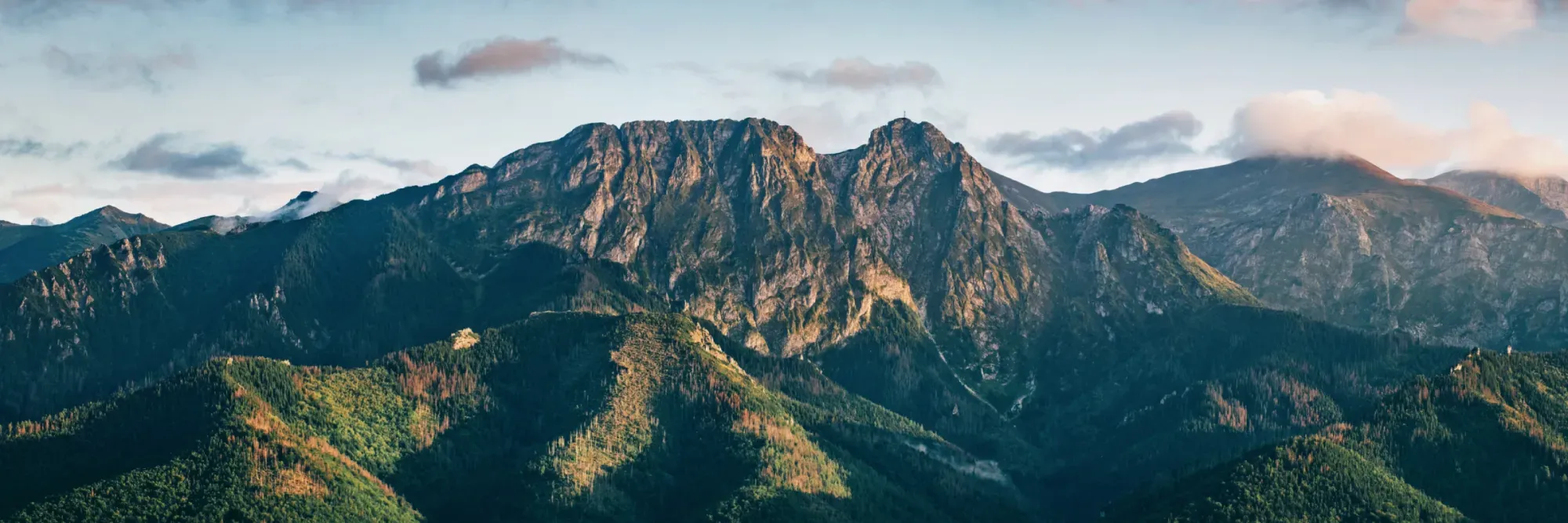 A pyramid stack of empty crystal champagne coupe glasses on a glass table with a dark background and soft lighting.