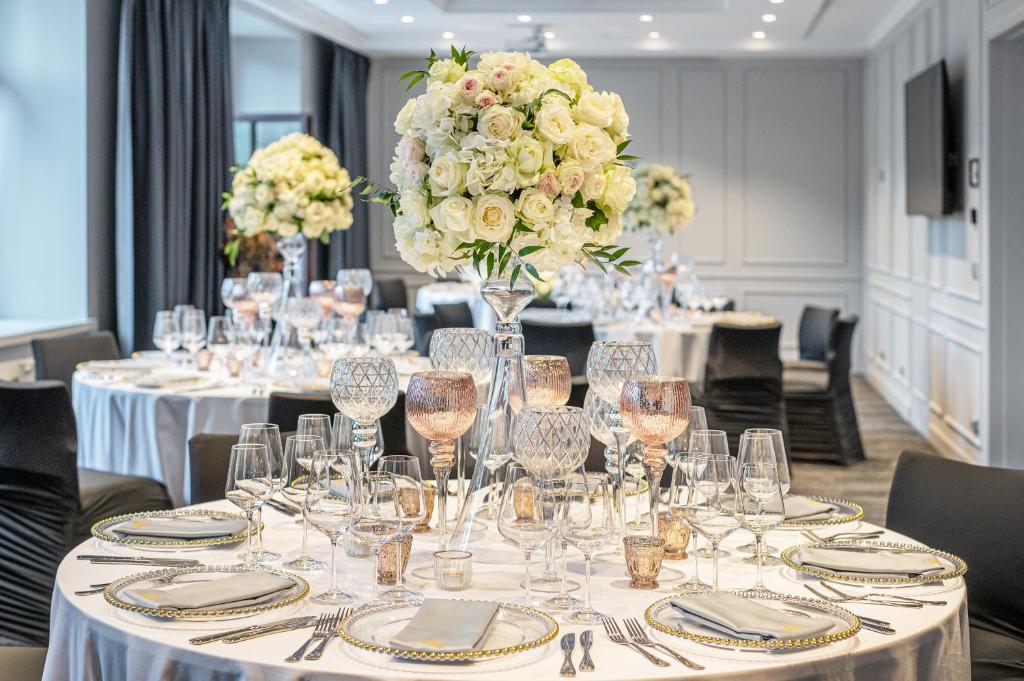 A pyramid stack of empty crystal champagne coupe glasses on a glass table with a dark background and soft lighting.