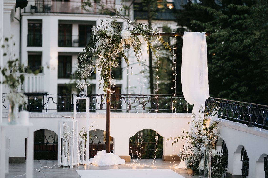 A pyramid stack of empty crystal champagne coupe glasses on a glass table with a dark background and soft lighting.