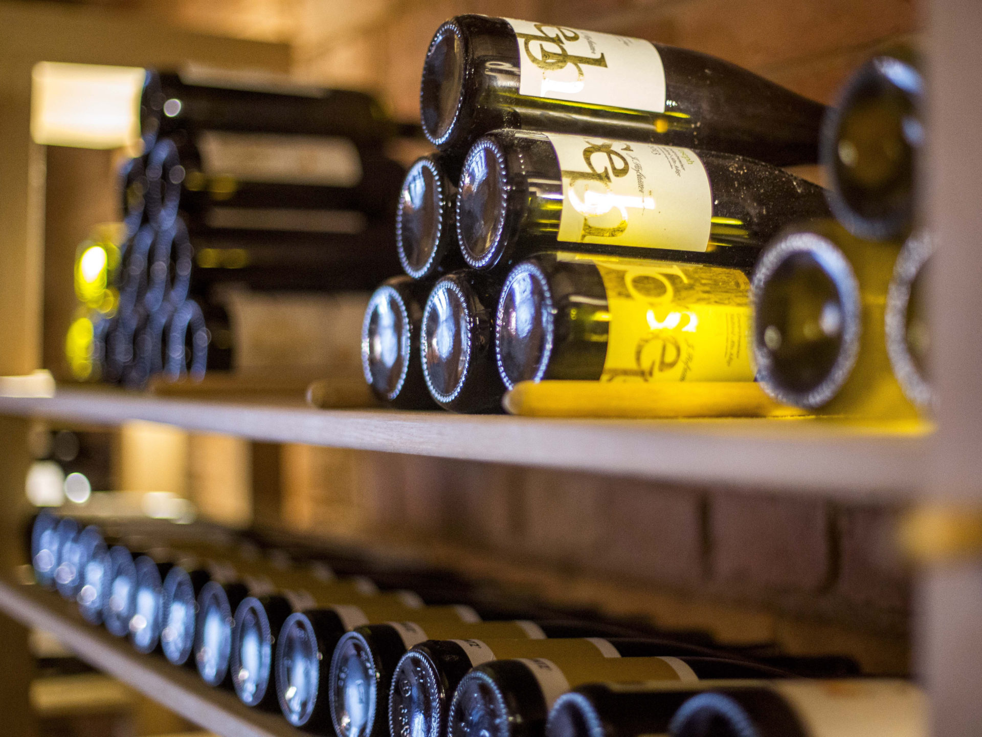 A pyramid stack of empty crystal champagne coupe glasses on a glass table with a dark background and soft lighting.