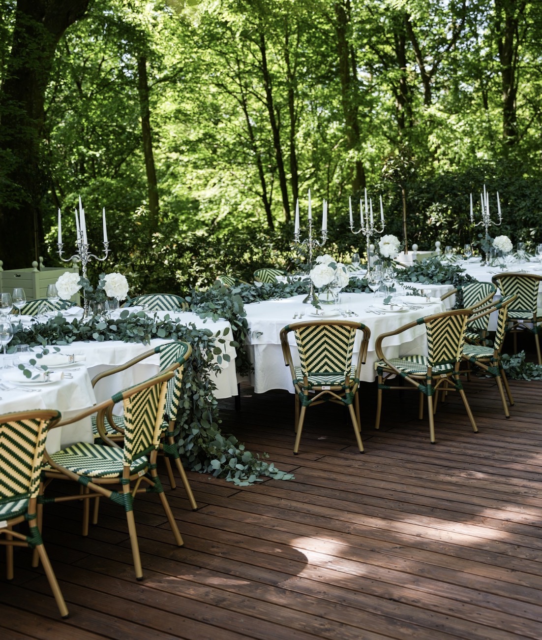 A pyramid stack of empty crystal champagne coupe glasses on a glass table with a dark background and soft lighting.