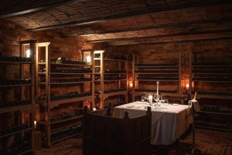 A pyramid stack of empty crystal champagne coupe glasses on a glass table with a dark background and soft lighting.