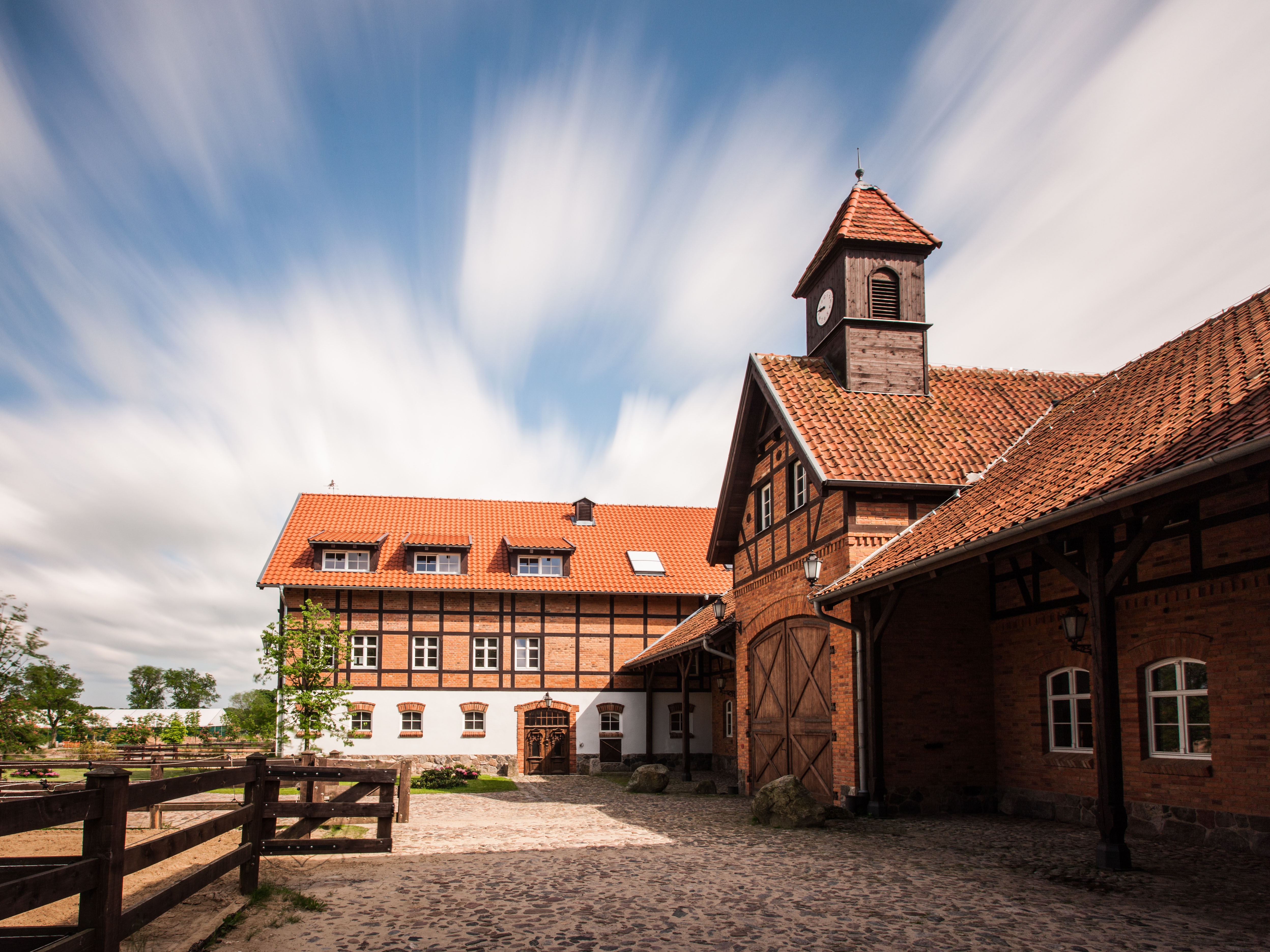 A pyramid stack of empty crystal champagne coupe glasses on a glass table with a dark background and soft lighting.