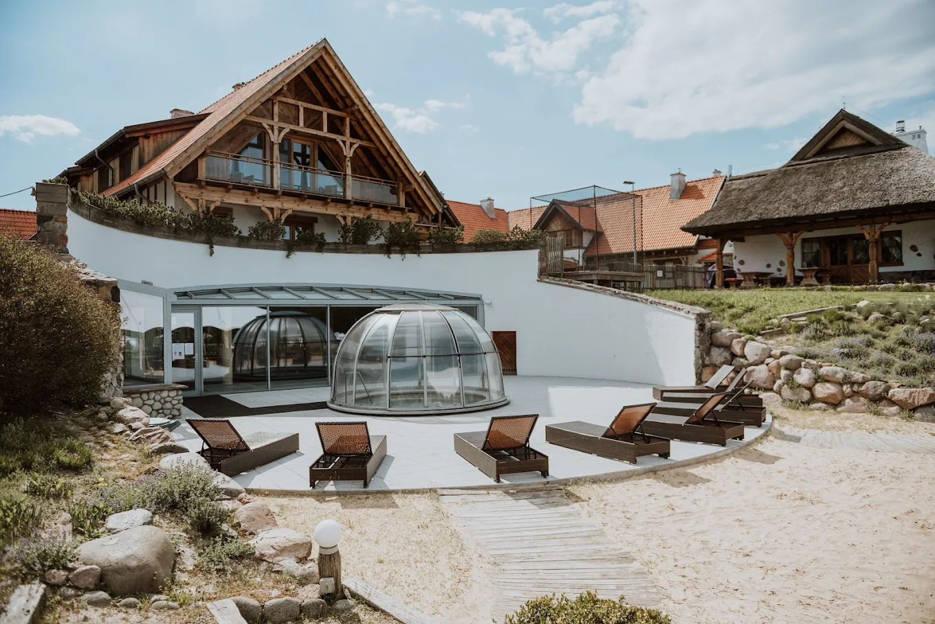 Cozy lodge interior with wooden walls, leather armchairs, stone fireplace, and decorative chandeliers.