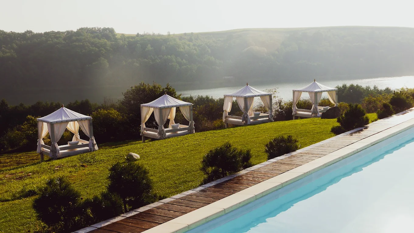 A pyramid stack of empty crystal champagne coupe glasses on a glass table with a dark background and soft lighting.