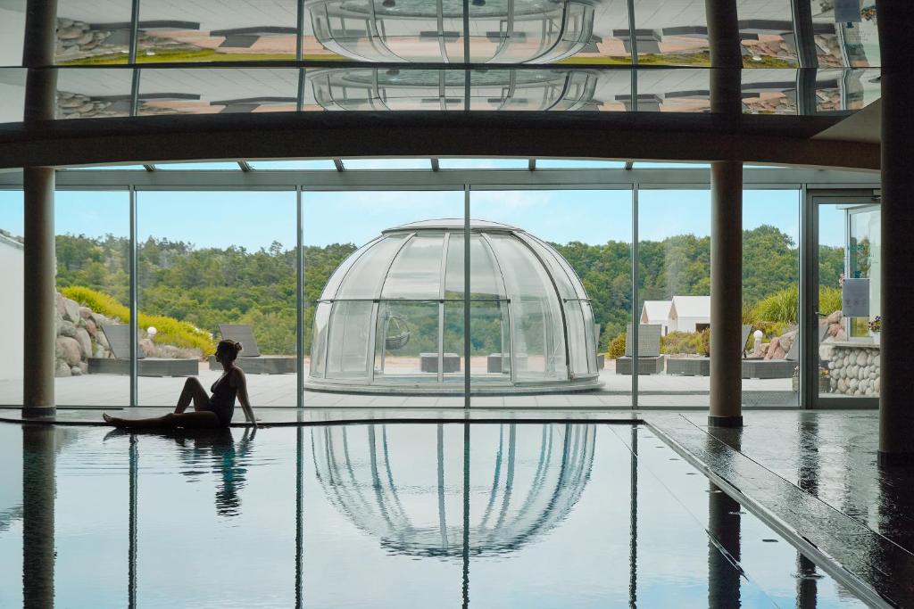 A pyramid stack of empty crystal champagne coupe glasses on a glass table with a dark background and soft lighting.