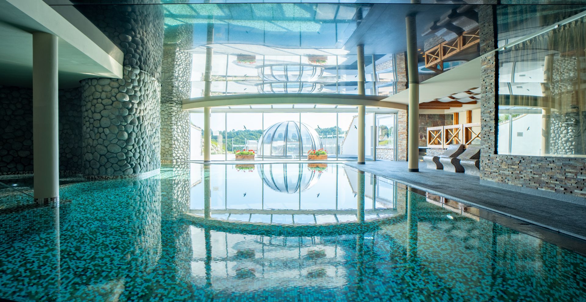 A pyramid stack of empty crystal champagne coupe glasses on a glass table with a dark background and soft lighting.