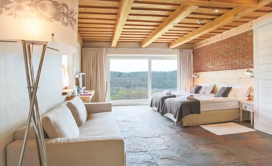 A pyramid stack of empty crystal champagne coupe glasses on a glass table with a dark background and soft lighting.