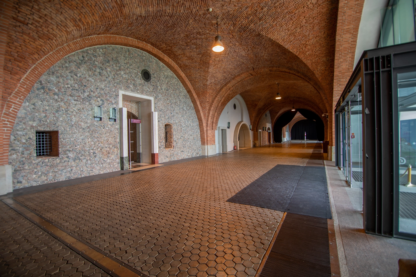A pyramid stack of empty crystal champagne coupe glasses on a glass table with a dark background and soft lighting.