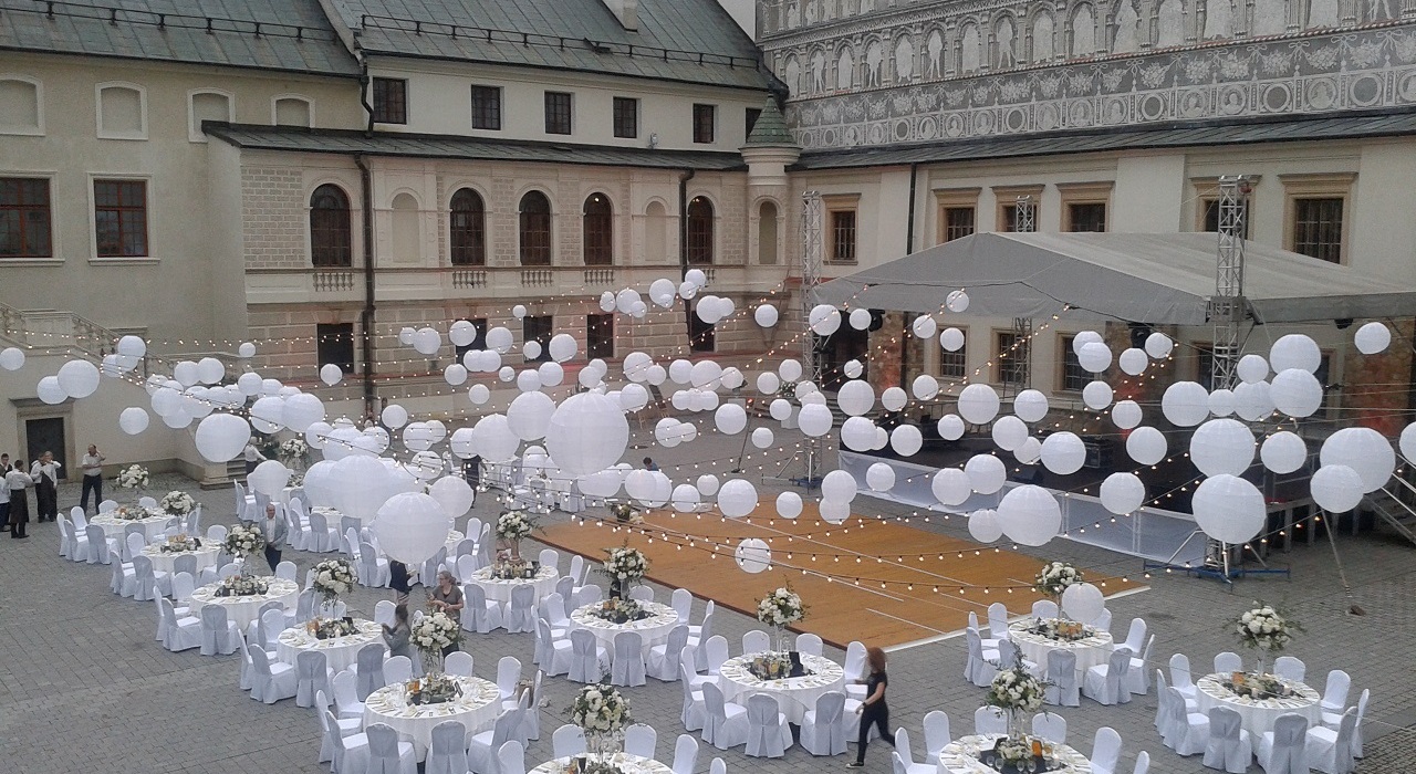 A pyramid stack of empty crystal champagne coupe glasses on a glass table with a dark background and soft lighting.