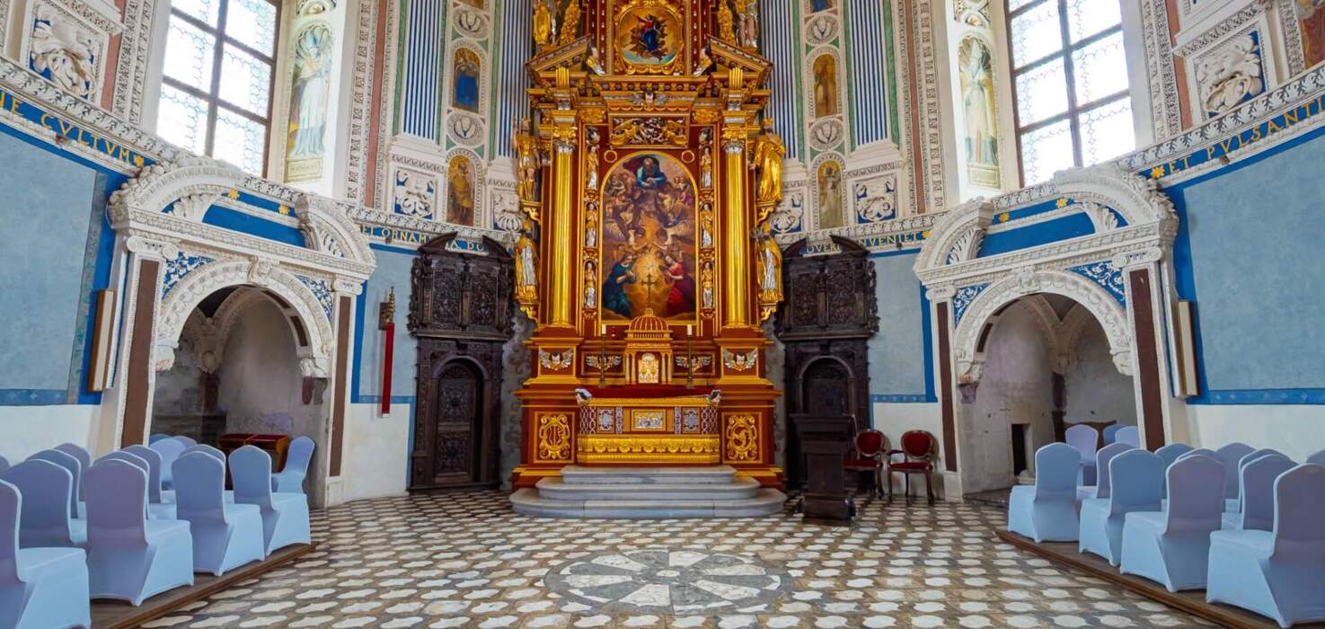 A pyramid stack of empty crystal champagne coupe glasses on a glass table with a dark background and soft lighting.