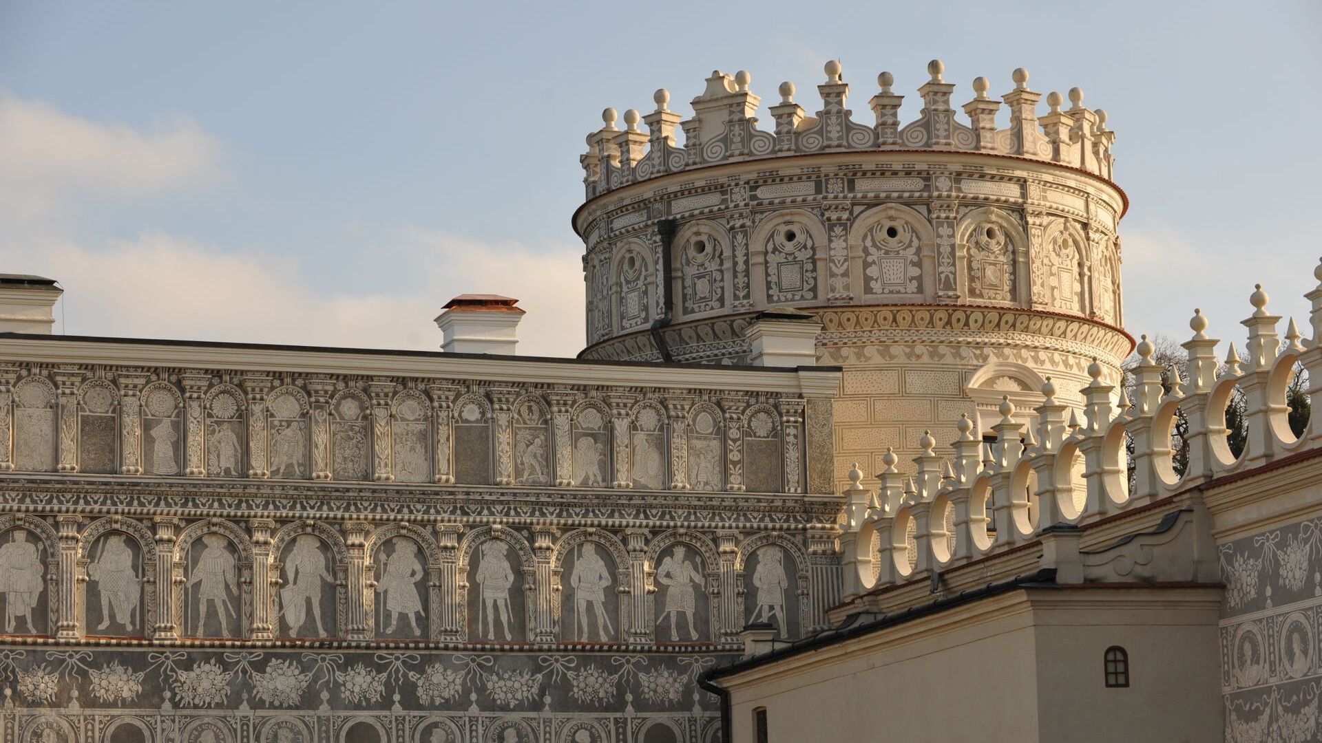 A pyramid stack of empty crystal champagne coupe glasses on a glass table with a dark background and soft lighting.
