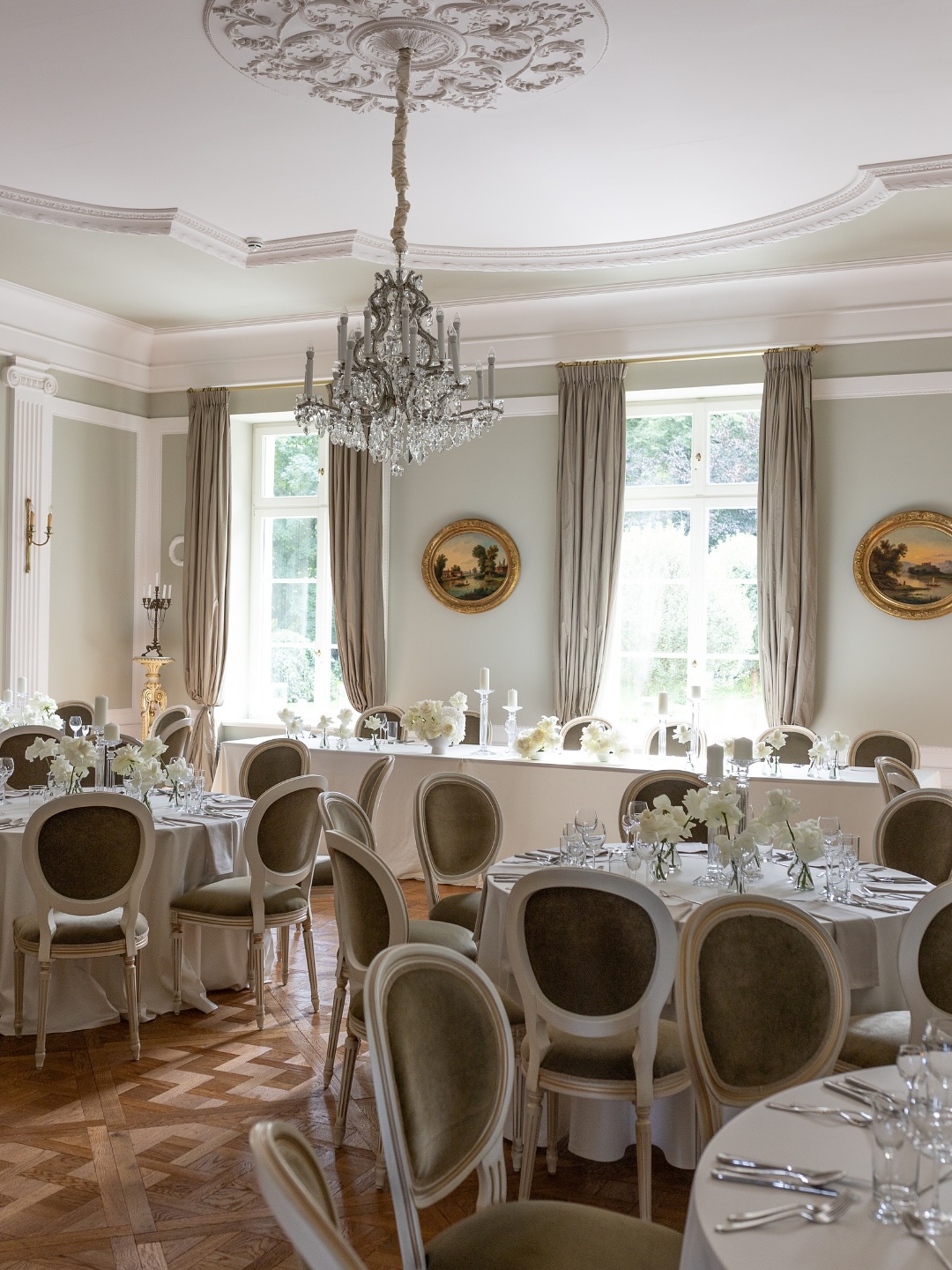 A pyramid stack of empty crystal champagne coupe glasses on a glass table with a dark background and soft lighting.