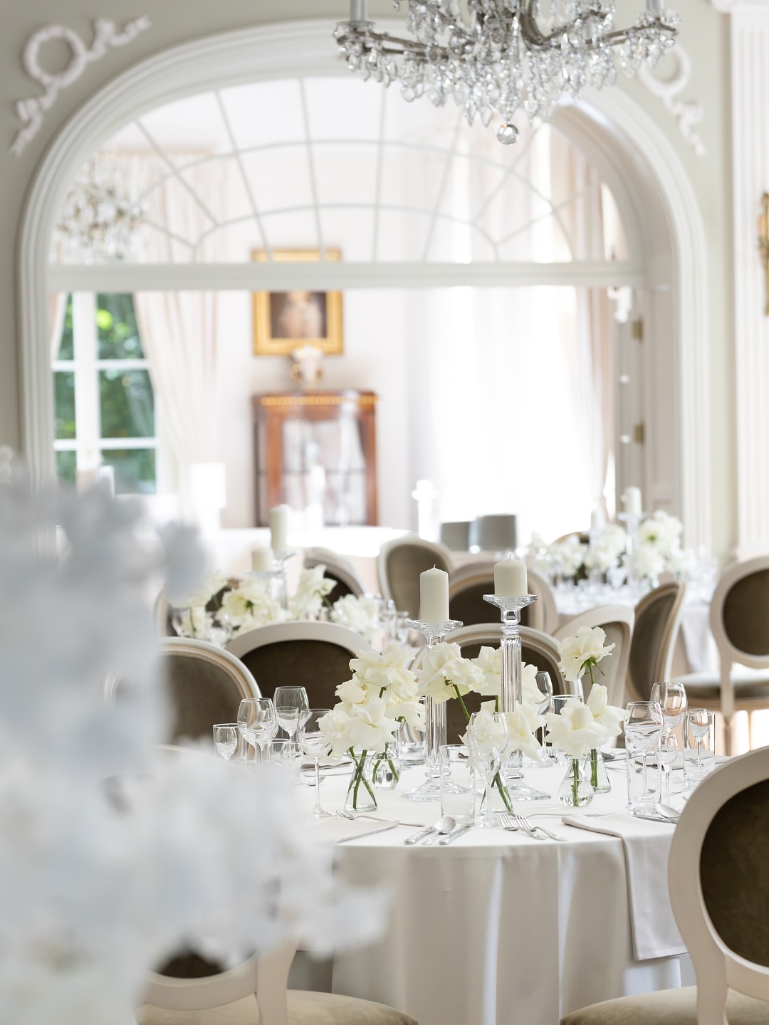 A pyramid stack of empty crystal champagne coupe glasses on a glass table with a dark background and soft lighting.