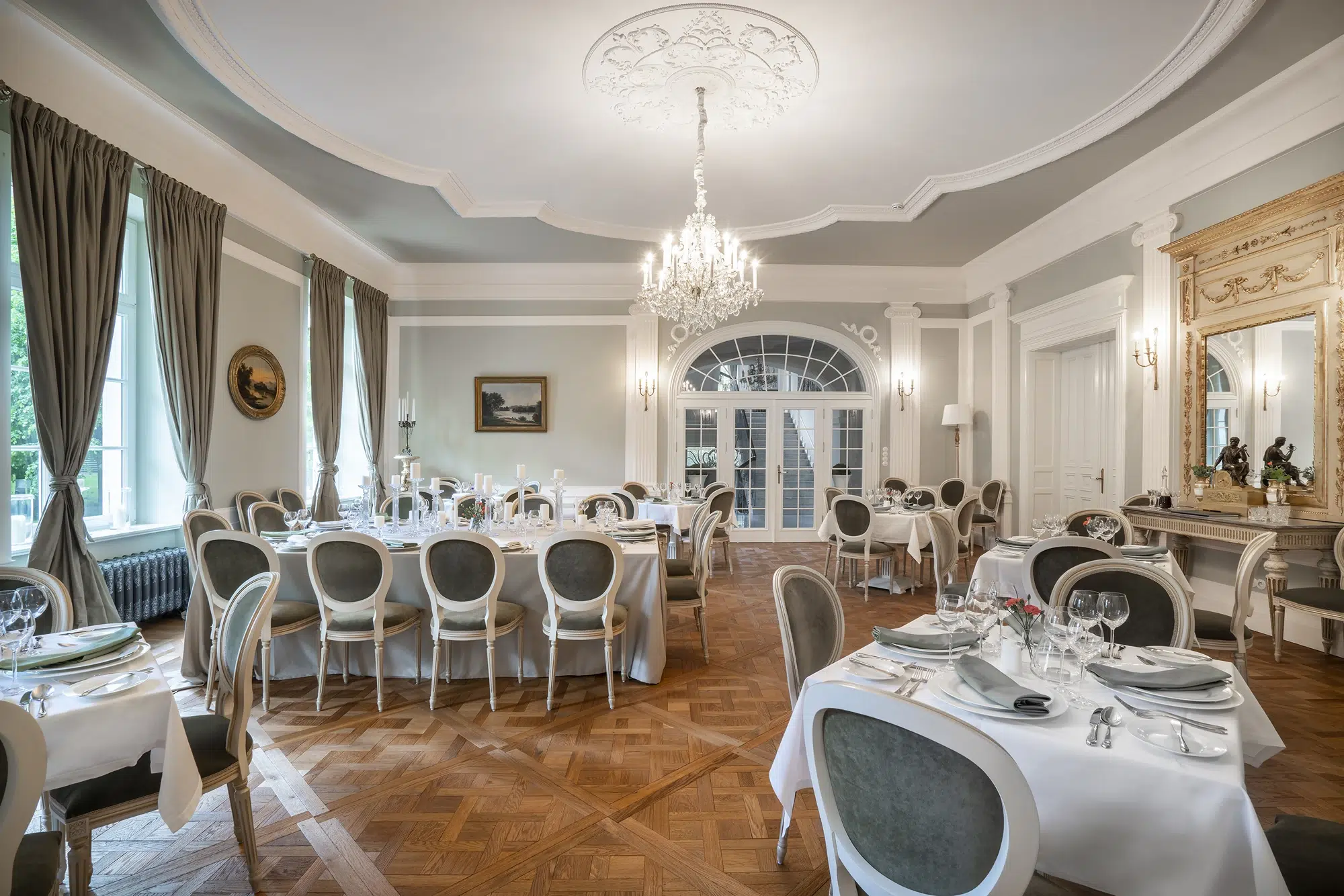 A pyramid stack of empty crystal champagne coupe glasses on a glass table with a dark background and soft lighting.
