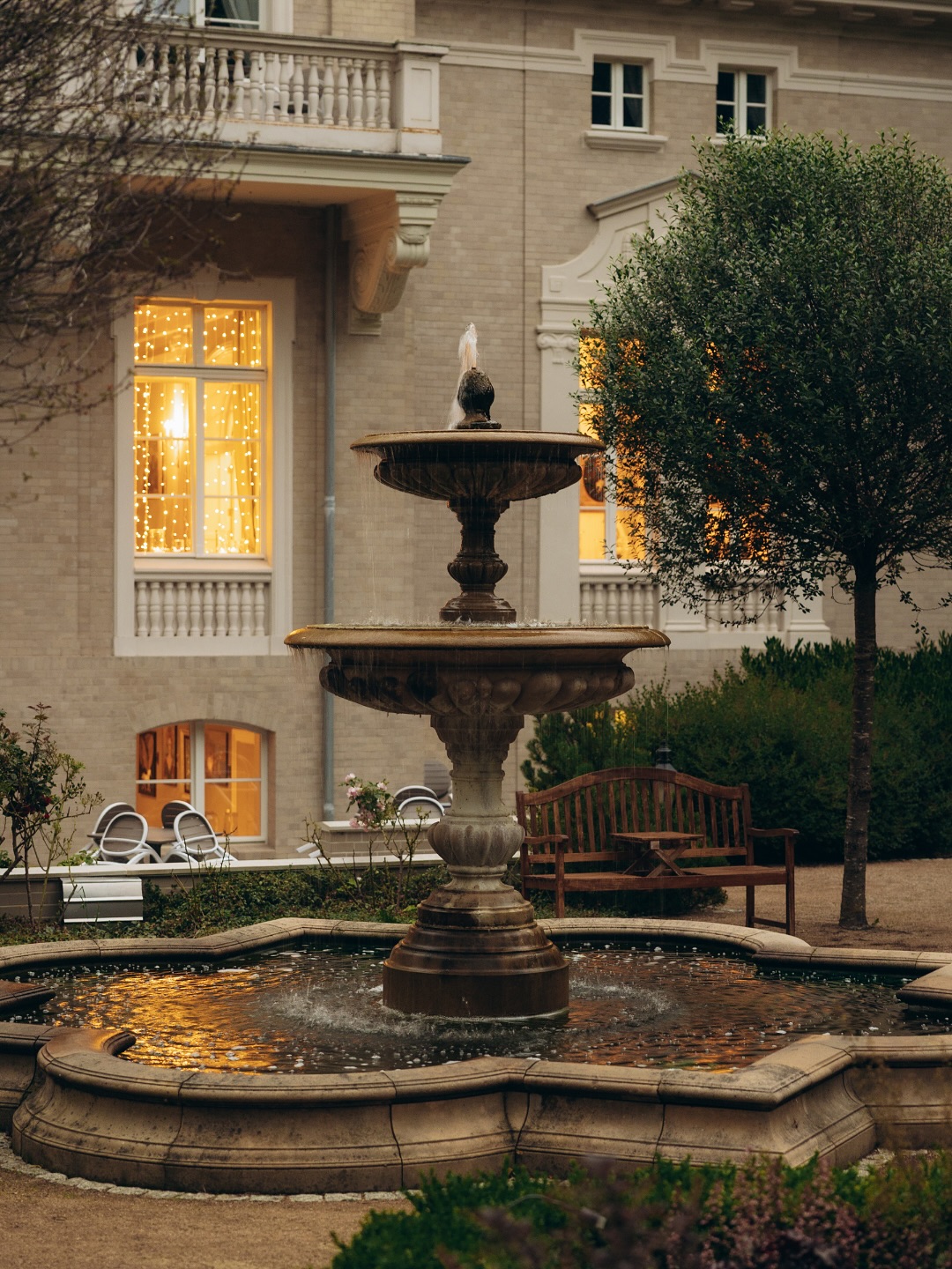 A pyramid stack of empty crystal champagne coupe glasses on a glass table with a dark background and soft lighting.