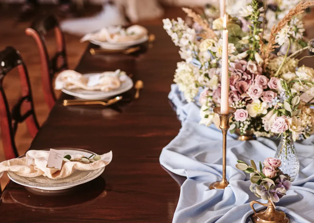 A pyramid stack of empty crystal champagne coupe glasses on a glass table with a dark background and soft lighting.