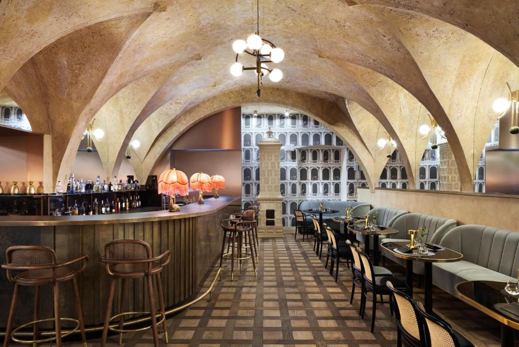 A pyramid stack of empty crystal champagne coupe glasses on a glass table with a dark background and soft lighting.