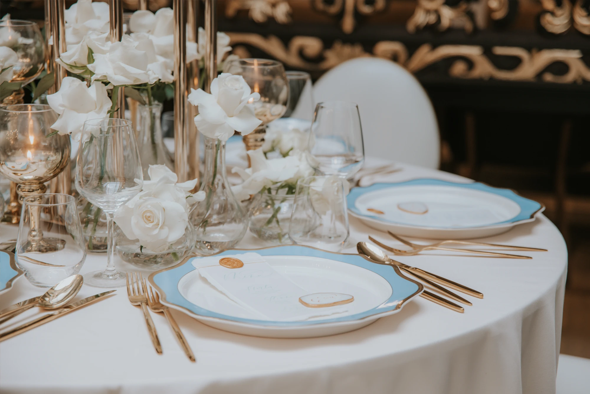 A pyramid stack of empty crystal champagne coupe glasses on a glass table with a dark background and soft lighting.