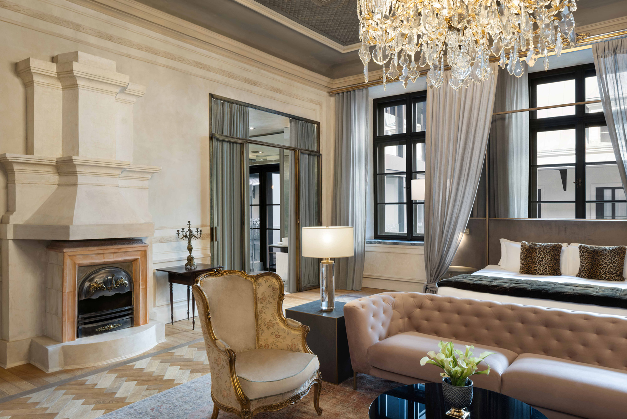 A pyramid stack of empty crystal champagne coupe glasses on a glass table with a dark background and soft lighting.