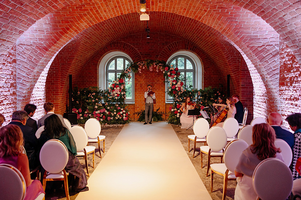 A pyramid stack of empty crystal champagne coupe glasses on a glass table with a dark background and soft lighting.