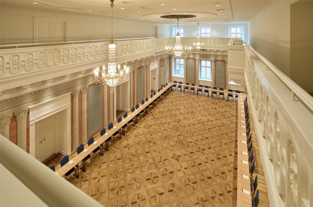 A pyramid stack of empty crystal champagne coupe glasses on a glass table with a dark background and soft lighting.