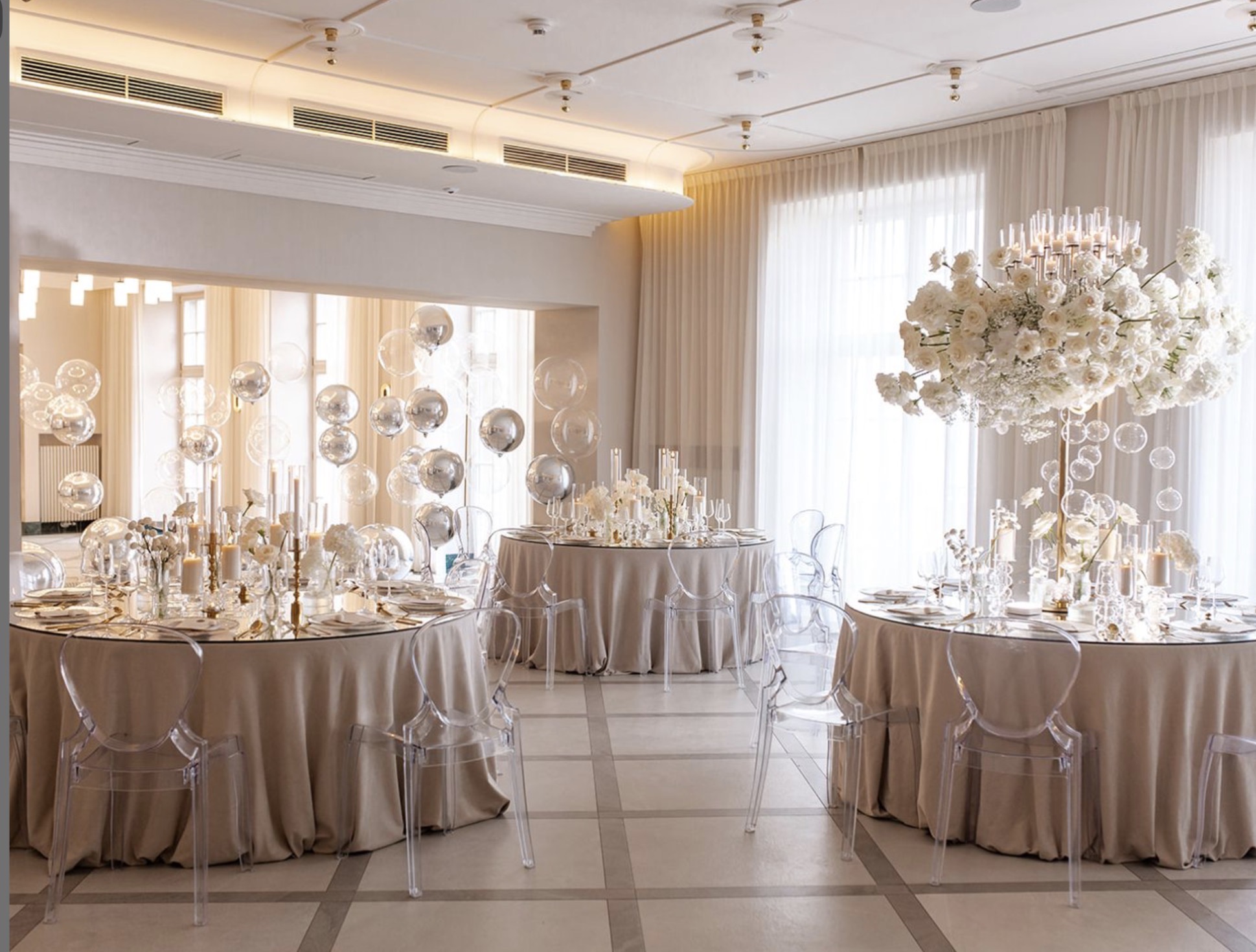 A pyramid stack of empty crystal champagne coupe glasses on a glass table with a dark background and soft lighting.