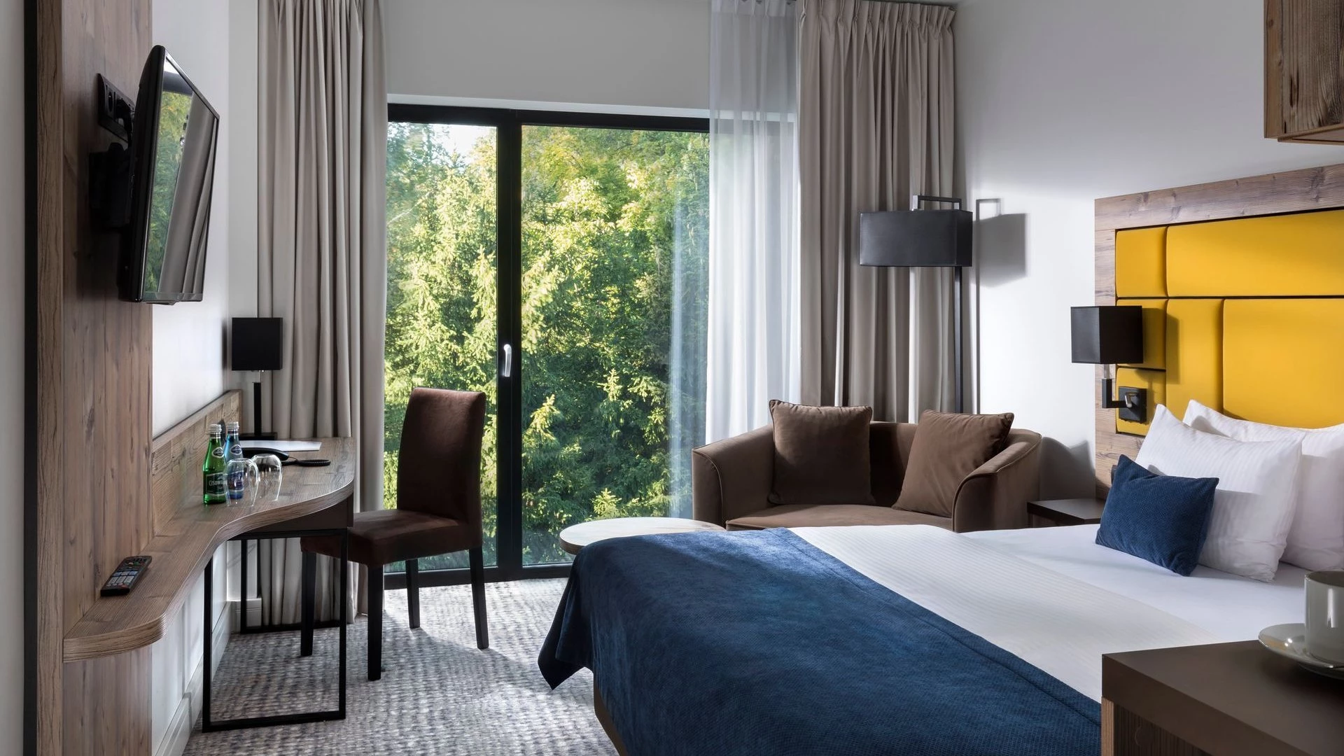 A pyramid stack of empty crystal champagne coupe glasses on a glass table with a dark background and soft lighting.