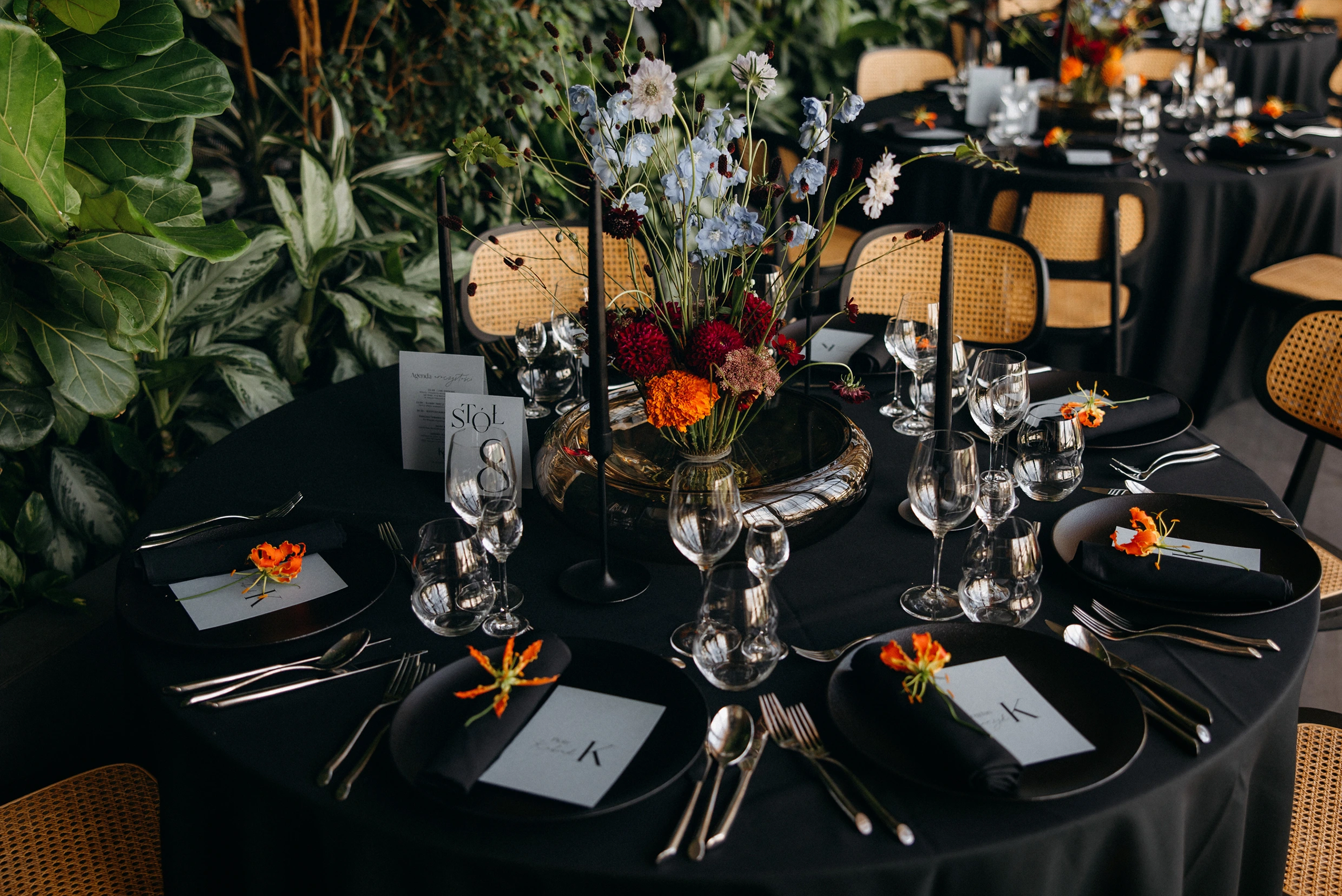 A pyramid stack of empty crystal champagne coupe glasses on a glass table with a dark background and soft lighting.