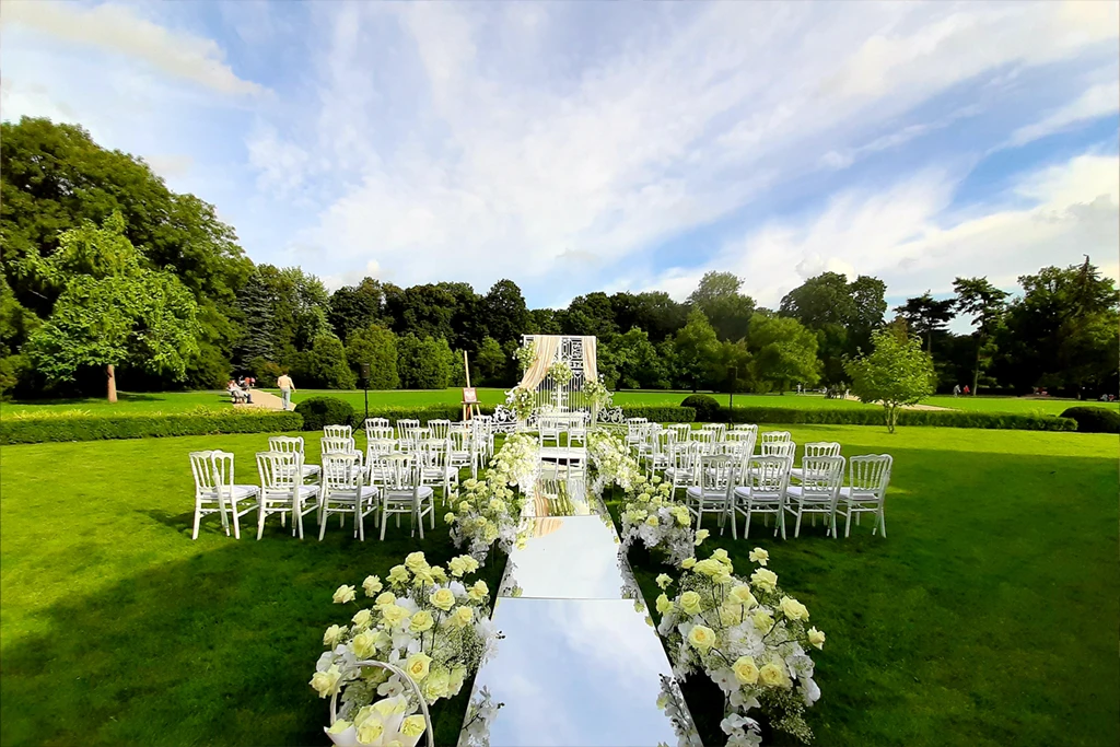 A pyramid stack of empty crystal champagne coupe glasses on a glass table with a dark background and soft lighting.