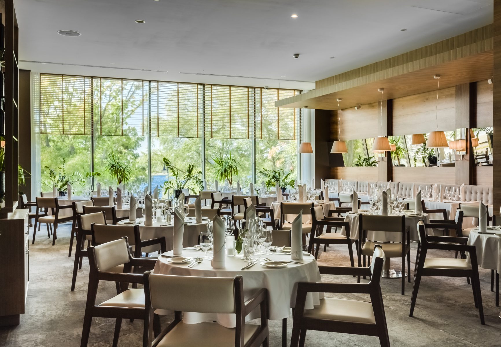 A pyramid stack of empty crystal champagne coupe glasses on a glass table with a dark background and soft lighting.