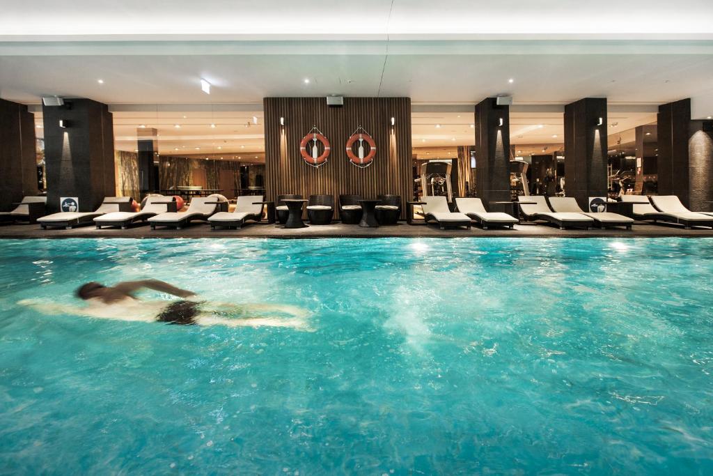 A pyramid stack of empty crystal champagne coupe glasses on a glass table with a dark background and soft lighting.