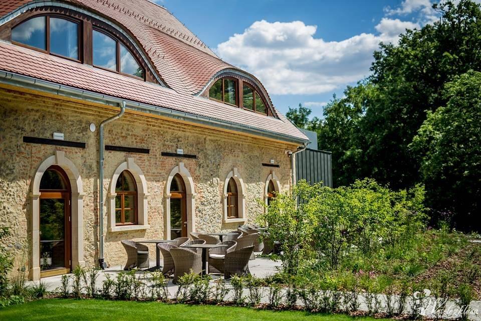 A pyramid stack of empty crystal champagne coupe glasses on a glass table with a dark background and soft lighting.