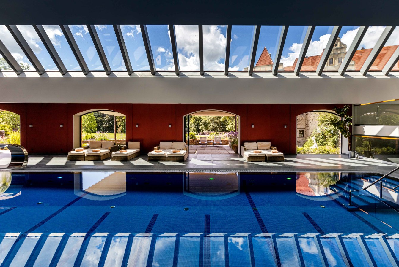 A pyramid stack of empty crystal champagne coupe glasses on a glass table with a dark background and soft lighting.