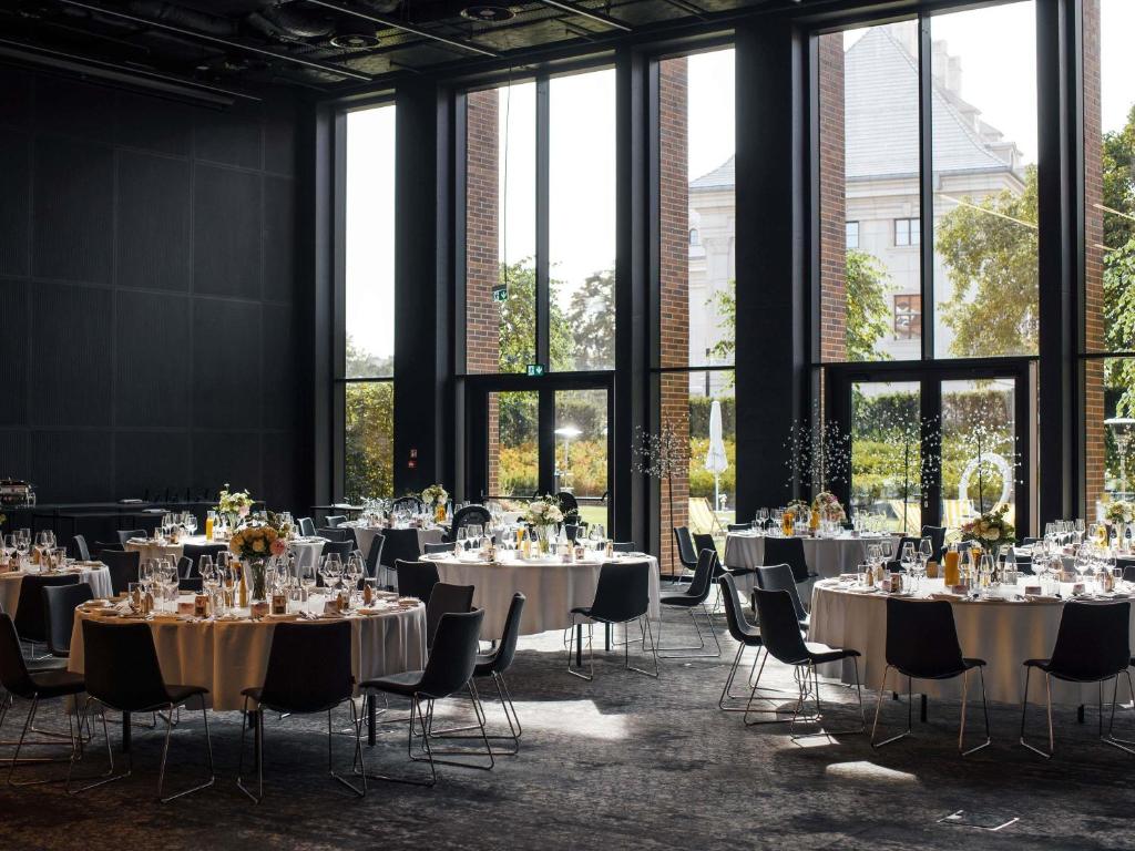A pyramid stack of empty crystal champagne coupe glasses on a glass table with a dark background and soft lighting.