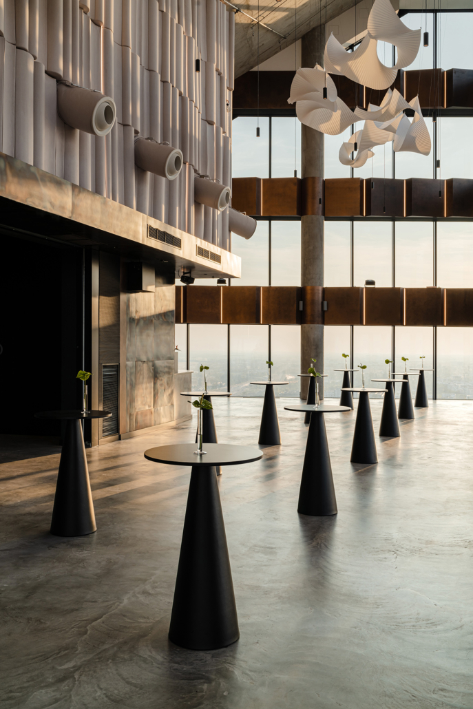 A pyramid stack of empty crystal champagne coupe glasses on a glass table with a dark background and soft lighting.