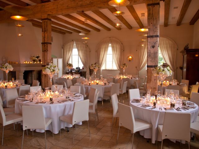 A pyramid stack of empty crystal champagne coupe glasses on a glass table with a dark background and soft lighting.