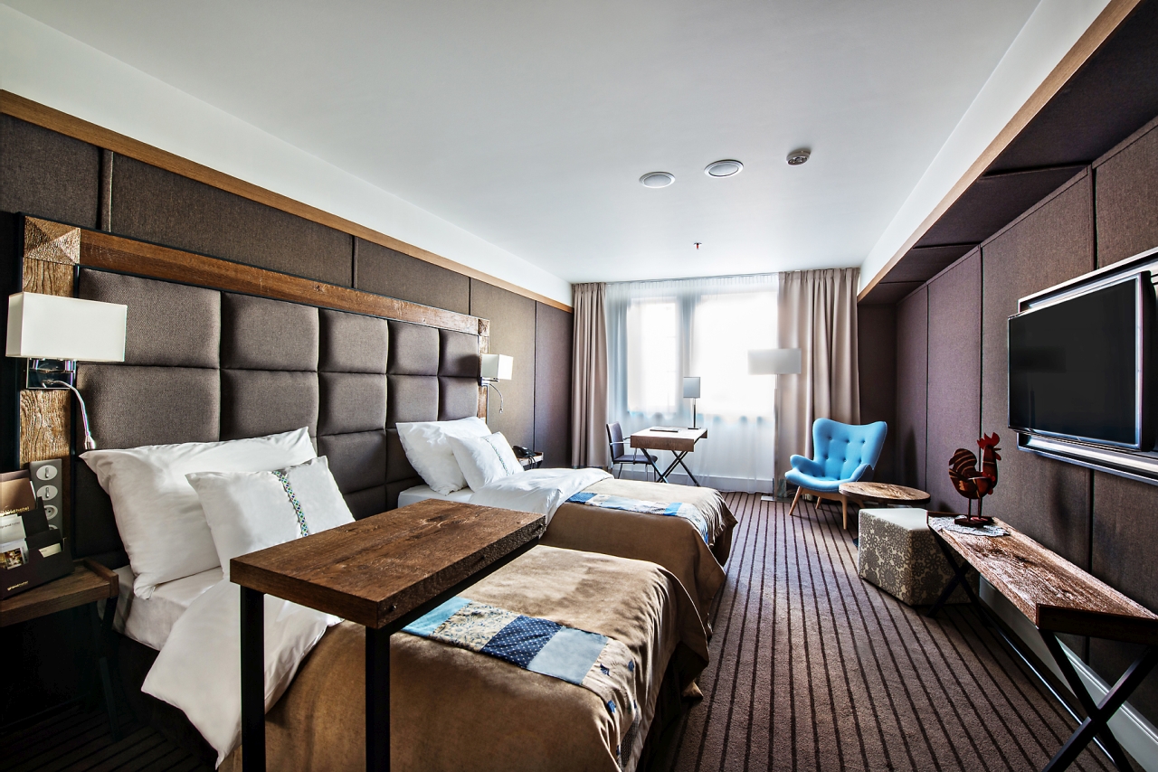 A pyramid stack of empty crystal champagne coupe glasses on a glass table with a dark background and soft lighting.