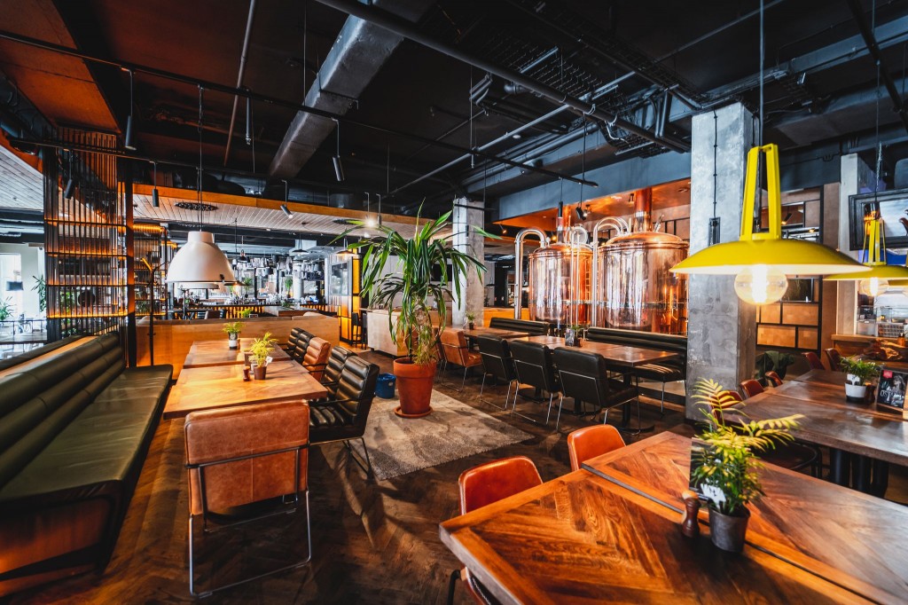 A pyramid stack of empty crystal champagne coupe glasses on a glass table with a dark background and soft lighting.