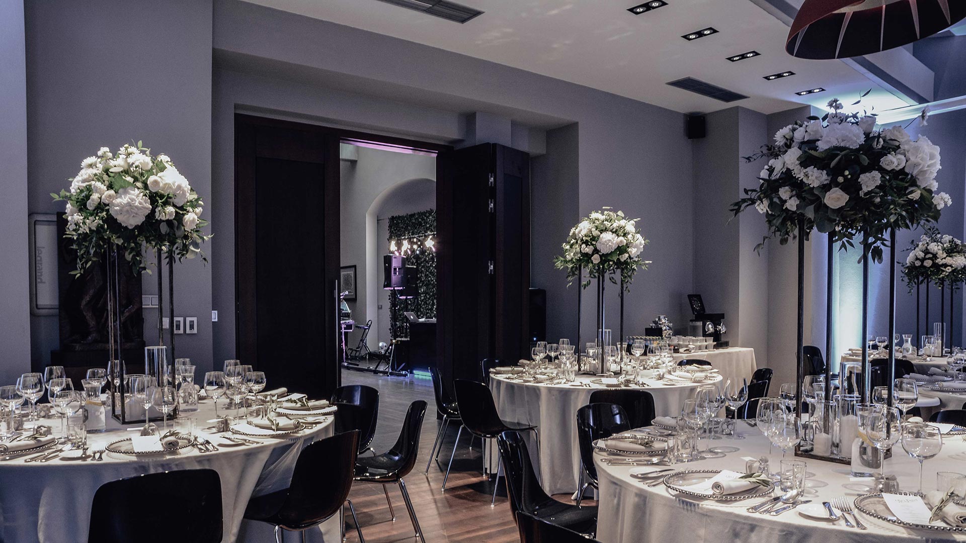 A pyramid stack of empty crystal champagne coupe glasses on a glass table with a dark background and soft lighting.
