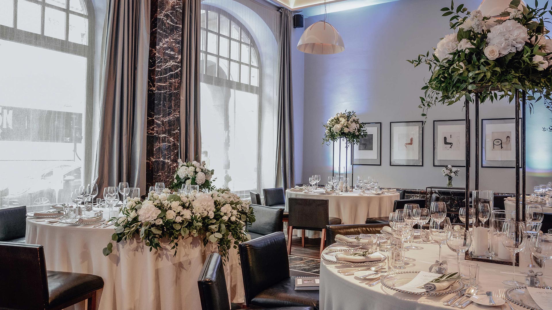A pyramid stack of empty crystal champagne coupe glasses on a glass table with a dark background and soft lighting.