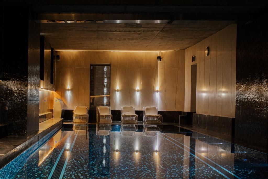 A pyramid stack of empty crystal champagne coupe glasses on a glass table with a dark background and soft lighting.