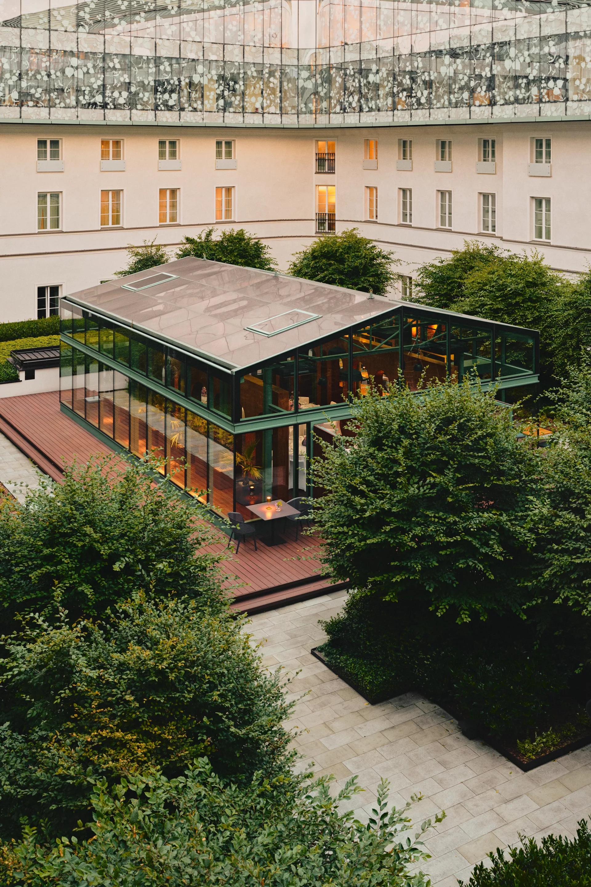 A pyramid stack of empty crystal champagne coupe glasses on a glass table with a dark background and soft lighting.