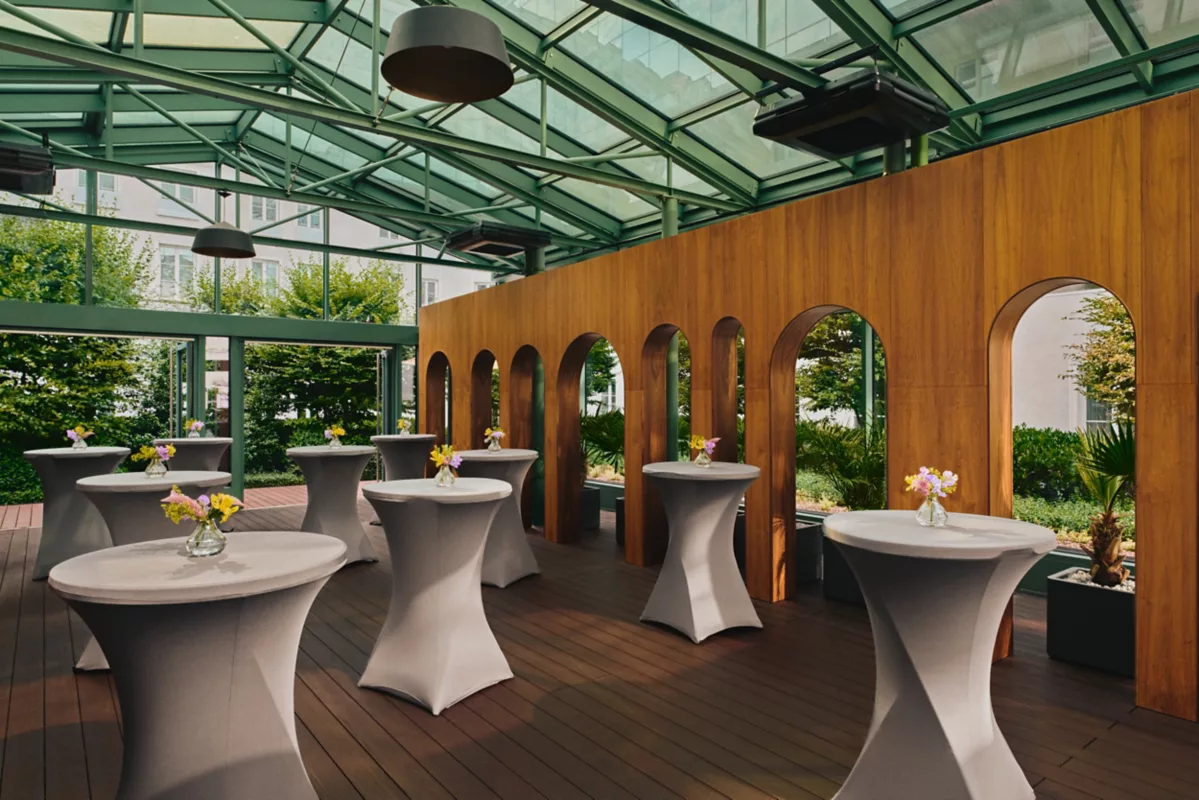 A pyramid stack of empty crystal champagne coupe glasses on a glass table with a dark background and soft lighting.