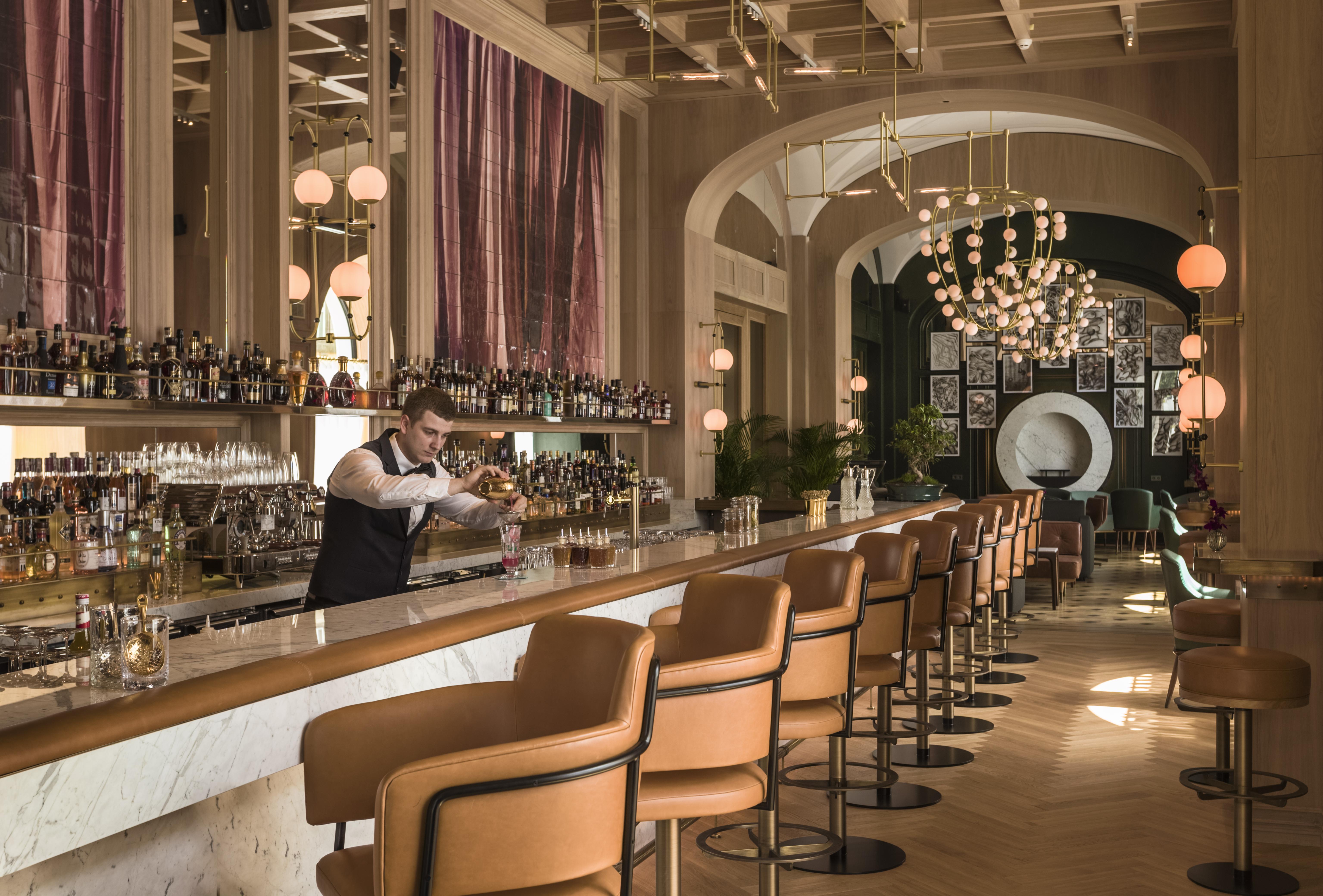 A pyramid stack of empty crystal champagne coupe glasses on a glass table with a dark background and soft lighting.